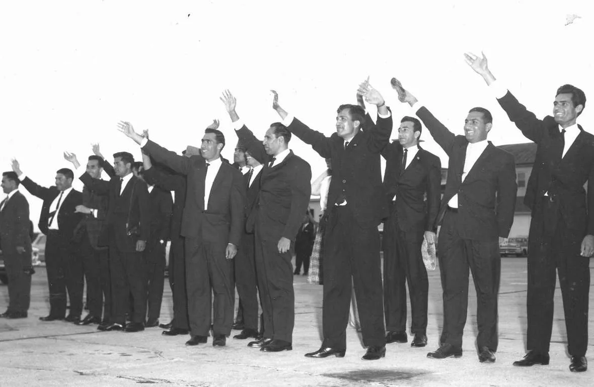 A group of Afghan students in dark suits waving as they arrive in the United States during the University of Wyoming Afghan Project era