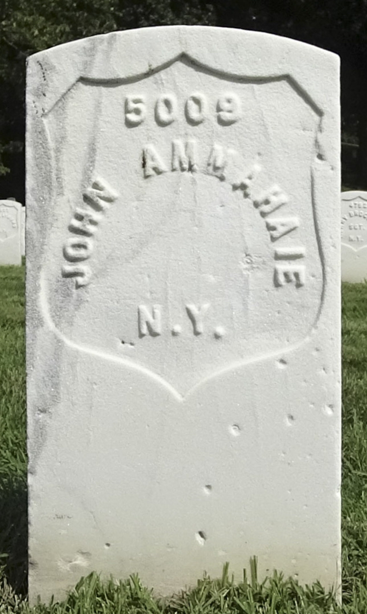 A white military headstone reading John Ammahaie, 5009, N.Y.